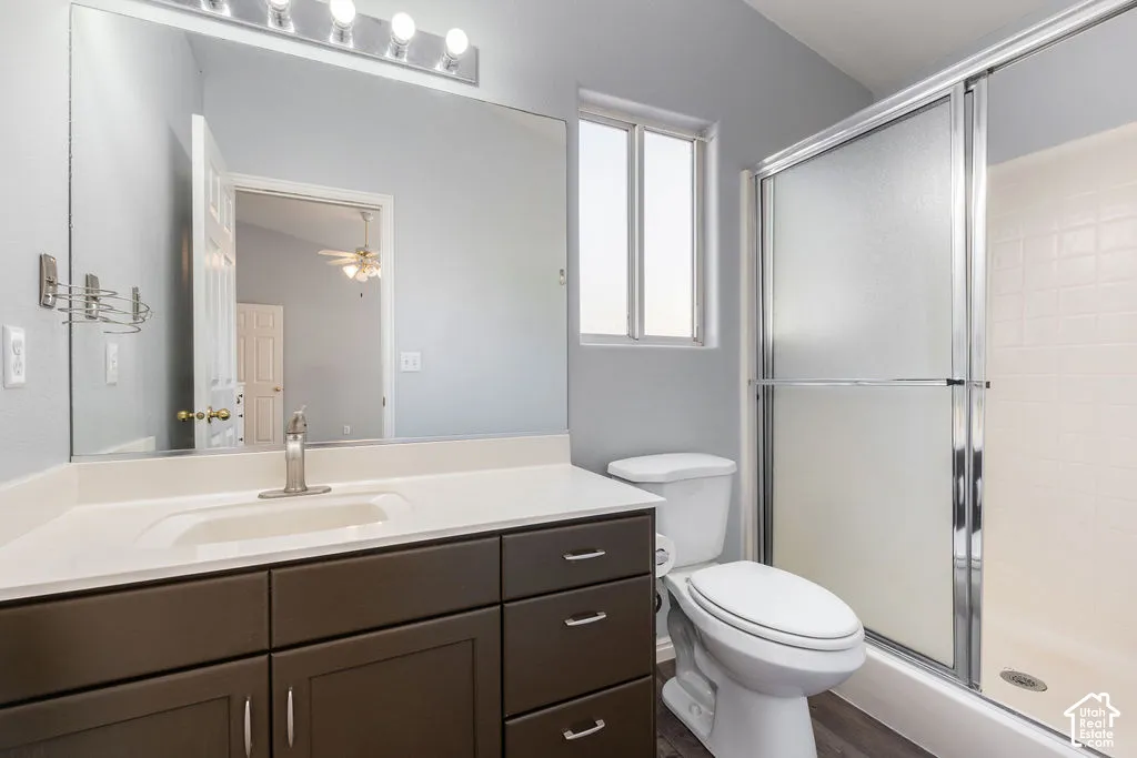 Bathroom featuring a dark wood-finish vanity with a white countertop, large wall-mounted mirror, polished chrome fixture, and a shower with sliding glass doors