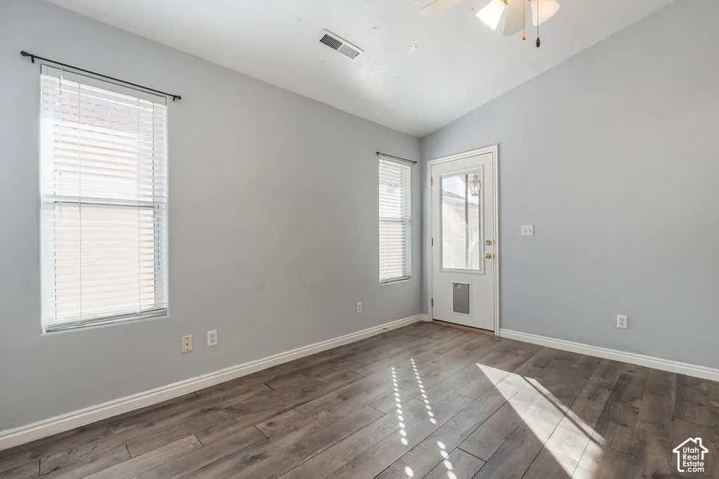 Vaulted ceilings, wood-finish flooring, dual windows with fitted blinds, and an exterior door featuring an integrated pet door