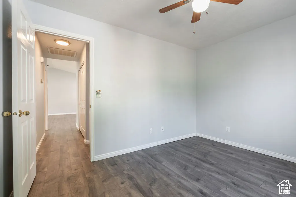 Room featuring wood-finish flooring, a ceiling fan with integrated lighting, and a six-panel interior door