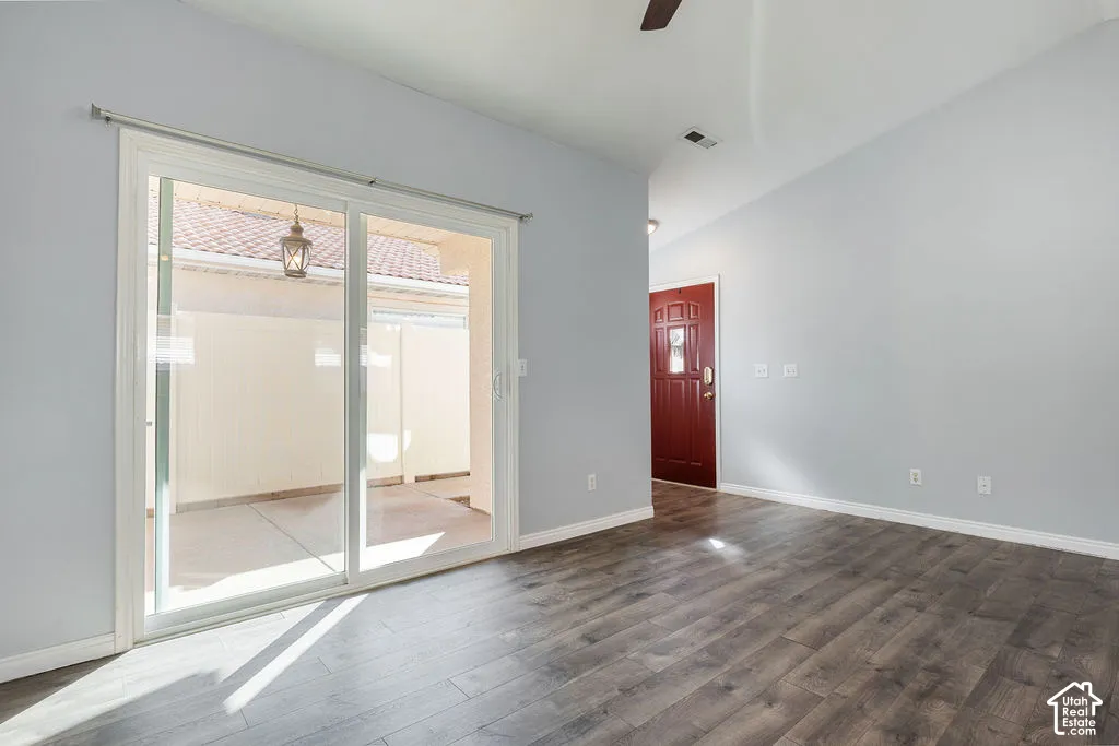 Wood-finish flooring, vaulted ceilings, sliding glass door, and a solid-core front door with decorative glass paneling