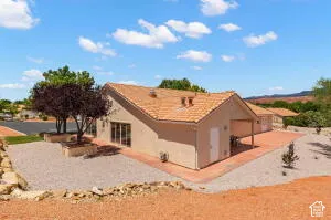 Stucco exterior featuring a clay tile roof, covered patio, and low-maintenance desert landscaping