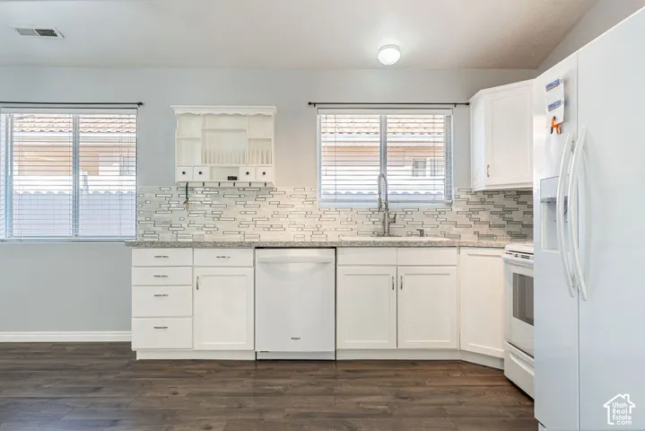 Kitchen featuring white cabinetry, stone-finish countertops, mosaic-tiled backsplash, integrated white appliances, and wood-finish flooring