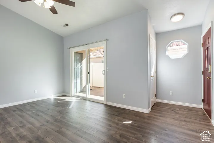 Vaulted ceiling with a central paddle fan, wood-finish flooring, sliding glass door, and decorative octagonal window