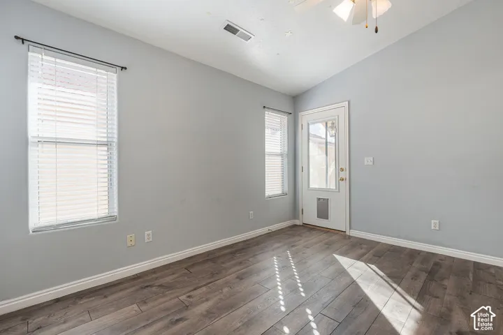 Vaulted ceilings, wood-finish flooring, dual windows with fitted blinds, and an exterior door featuring an integrated pet door