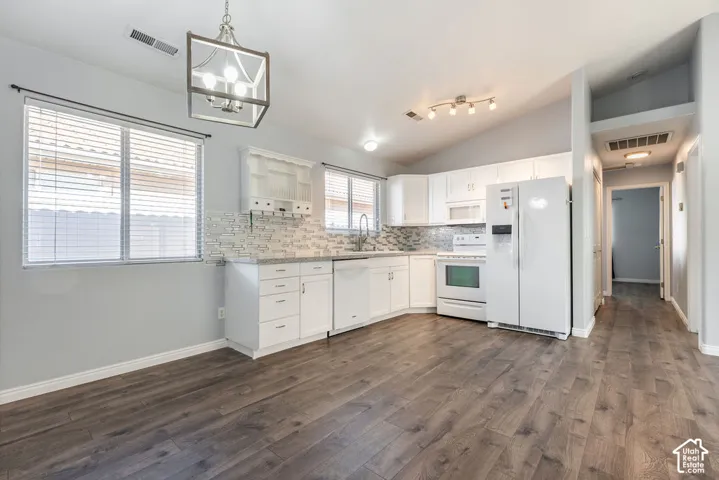 Kitchen featuring white cabinetry, stone-finish countertops, geometric tile backsplash, wood-finish flooring, and a metal lantern-style chandelier