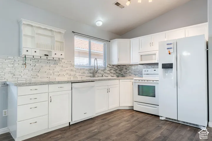 Kitchen featuring white cabinetry, stone-finish countertops, decorative tile backsplash, wood-finish flooring, and integrated white appliances