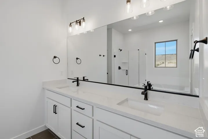 Dual-sink vanity with a solid-surface countertop, white shaker-style cabinetry, matte black hardware, and an expansive wall-mounted mirror