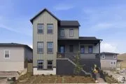 Multi-story residence featuring vertical siding, a stone veneer foundation, a raised covered porch, and a metal-railing staircase