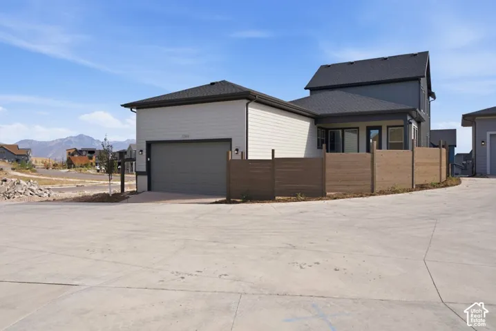 Two-story exterior with horizontal siding, attached garage, wood-style privacy fencing, and mountain backdrop