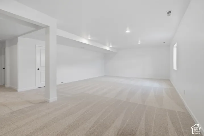 Expansive room featuring wall-to-wall carpeting, recessed ceiling lighting, and a neutral color palette