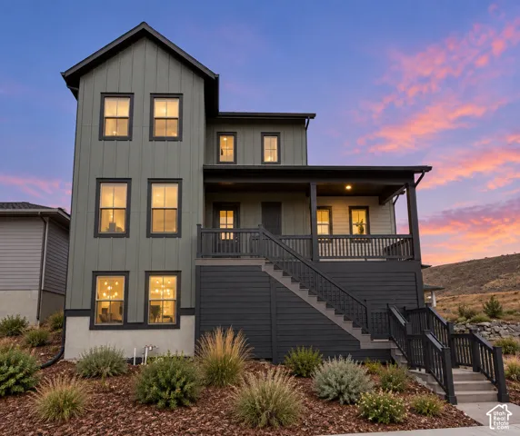 Three-story exterior featuring vertical board-and-batten siding, a covered deck with horizontal wood railing, and an elevated staircase