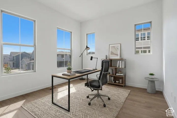 Neutral-toned interior space featuring wood-finish flooring, white walls, and four single-hung windows