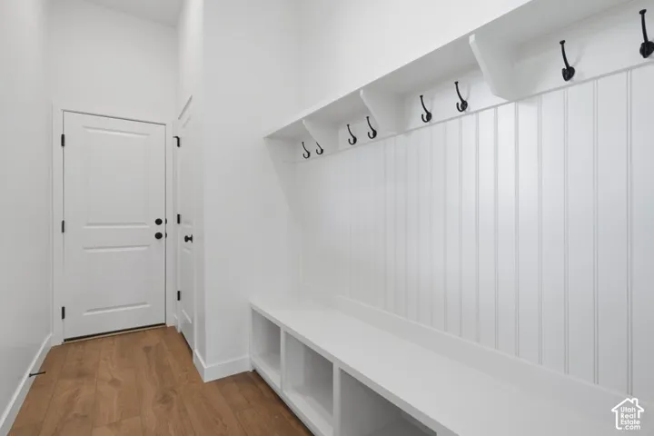 Built-in white storage bench with open cubbies, vertical beadboard wall paneling, integrated shelving, and matte black hardware