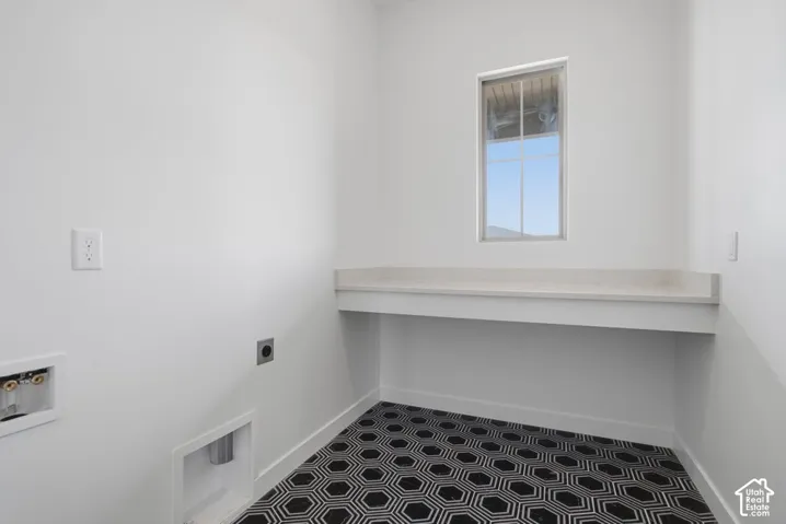 Utility space featuring a built-in countertop, geometric patterned tile flooring, and a single window