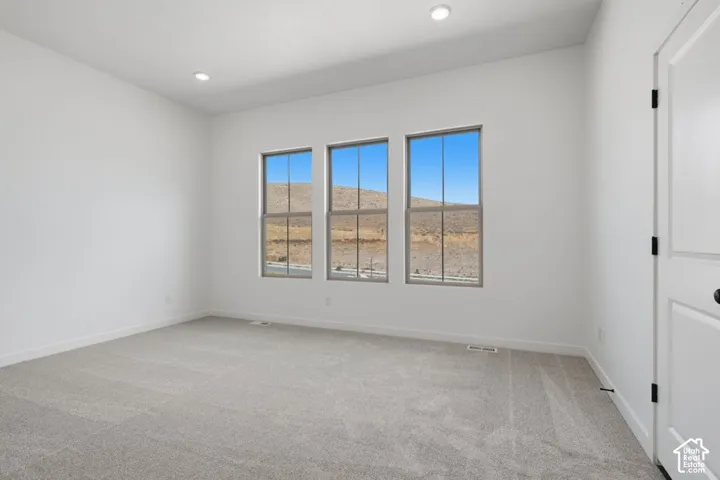 Neutral-toned carpeting, recessed ceiling lighting, and three windows featuring exterior mountain scenery