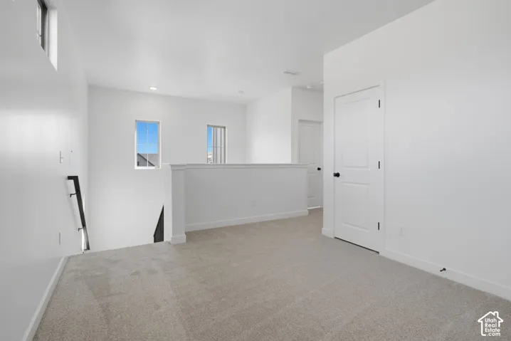 Neutral-toned carpeted flooring, white walls, recessed ceiling lighting, multi-pane windows, and interior doors with matte black hardware