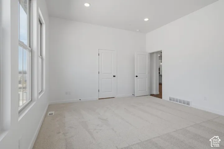 Room featuring high ceilings, neutral wall-to-wall carpeting, recessed lighting, and multi-pane windows