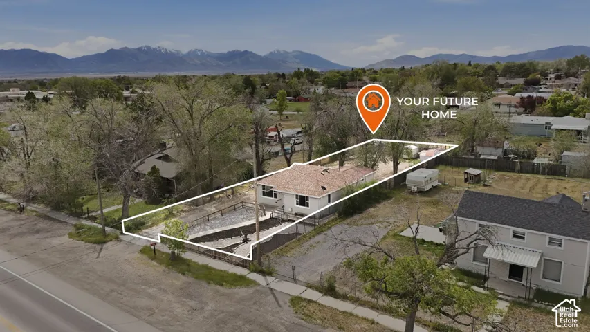 Single-story residence featuring a shingled roof, light-colored exterior siding, and a mountain backdrop