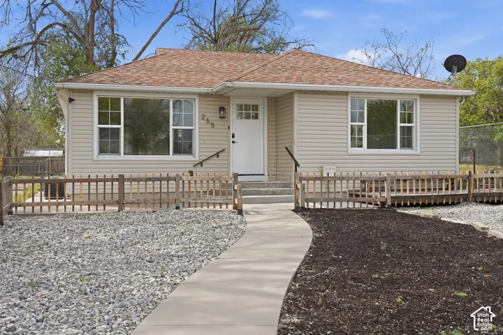 Single-story residence with horizontal siding, a composite shingle roof, multi-pane windows, and a paved walkway leading to the front entrance