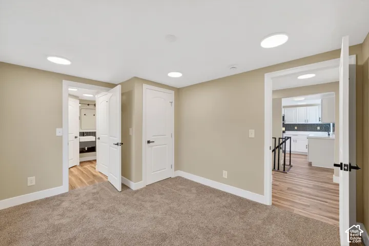 Neutral-toned interior space featuring recessed ceiling lighting, wall-to-wall carpeting, and solid-core interior doors with matte black hardware