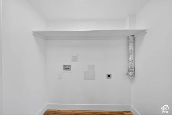 Utility area featuring wood-finish flooring, a built-in overhead storage shelf, and dedicated washer and dryer hookups