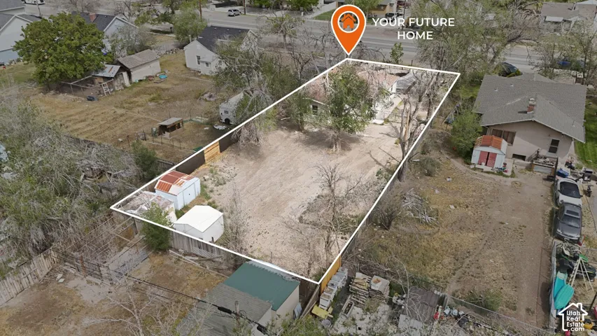 Expansive lot featuring mature trees, partial perimeter wood fencing, and detached storage structures