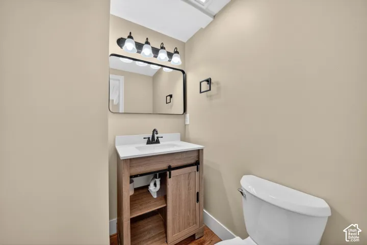 Wood-finish vanity with a sliding barn-style door, white countertop with an integrated rectangular sink, matte black faucet, and a rectangular mirror with a black frame
