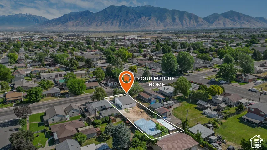 Aerial perspective of a residential lot featuring mountain scenery and a detached structure with metal roofing