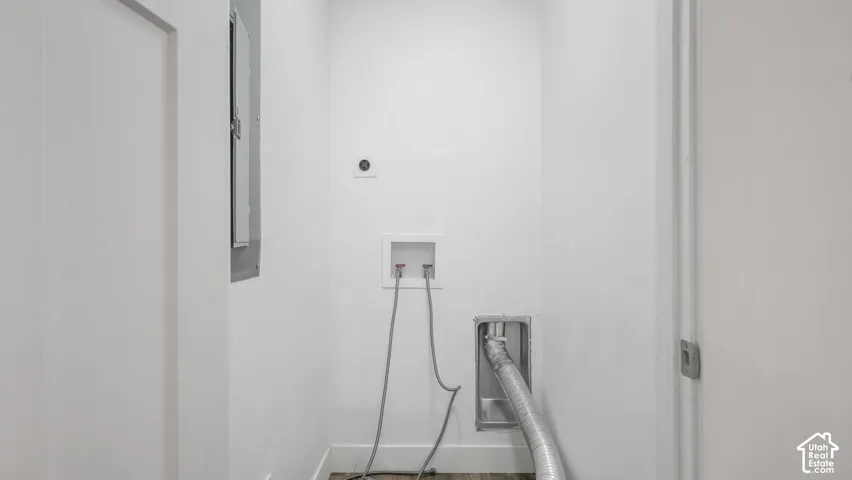 Utility space featuring laundry hookups, wall-mounted electrical panel, recessed dryer venting, and wood-finish flooring