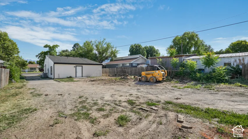 Detached structure with a white exterior, expansive lot, and perimeter wood fencing