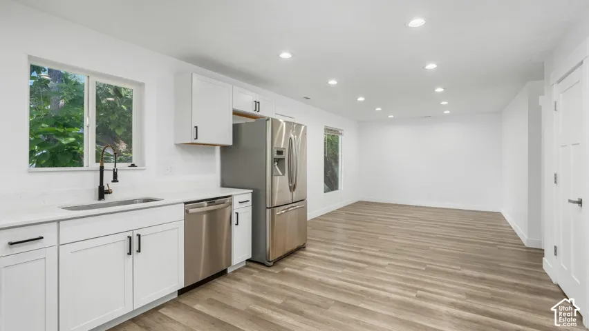 Kitchen featuring white shaker-style cabinetry, quartz countertops, stainless steel appliances, wood-finish flooring, and recessed ceiling lighting