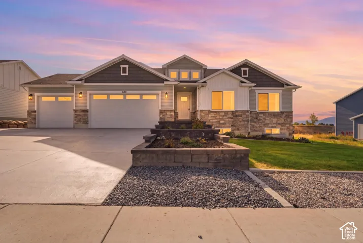 Multi-gabled exterior featuring horizontal siding, vertical board-and-batten accents, stone veneer foundation, and a three-car garage