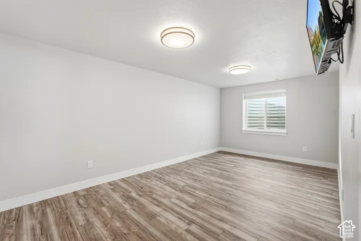 Neutral-toned interior featuring wood-finish flooring, two flush-mount ceiling light fixtures, and a window with integrated blinds