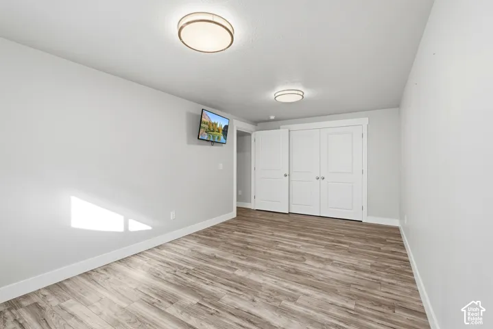 Room featuring wood-finish flooring, dual flush-mount ceiling light fixtures, and white paneled closet doors