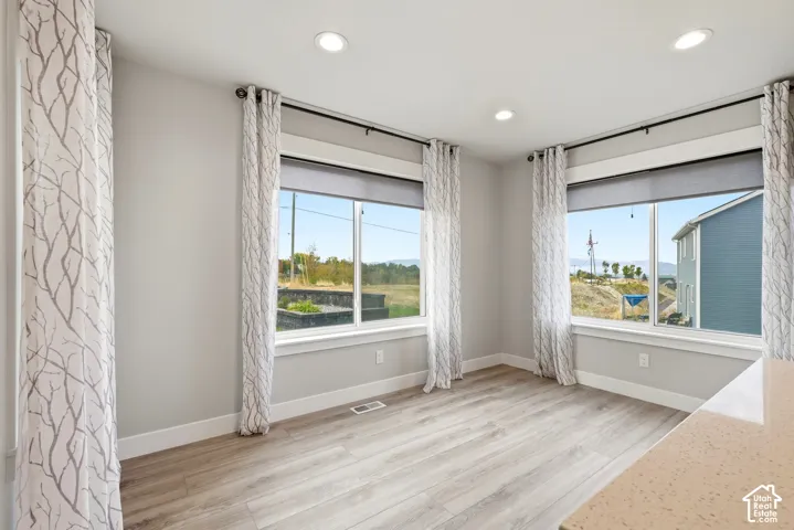 Wood-finish flooring, recessed lighting, and dual windows with light-filtering shades
