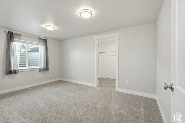 Neutral-toned room featuring wall-to-wall carpeting, flush-mount ceiling lighting, window with a sliding pane, and a reach-in closet with built-in hanging rod