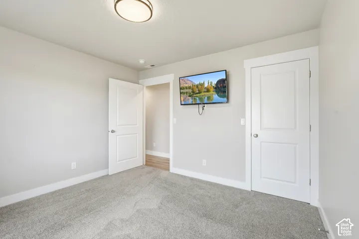 Neutral-toned walls, high-pile carpeting, two-panel interior doors, crisp white door casings, and a central flush-mount light fixture