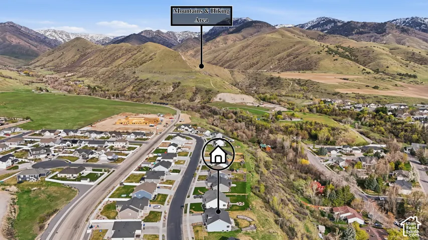 Aerial perspective featuring residential lots with manicured lawns, paved street infrastructure, and proximity to mountain terrain