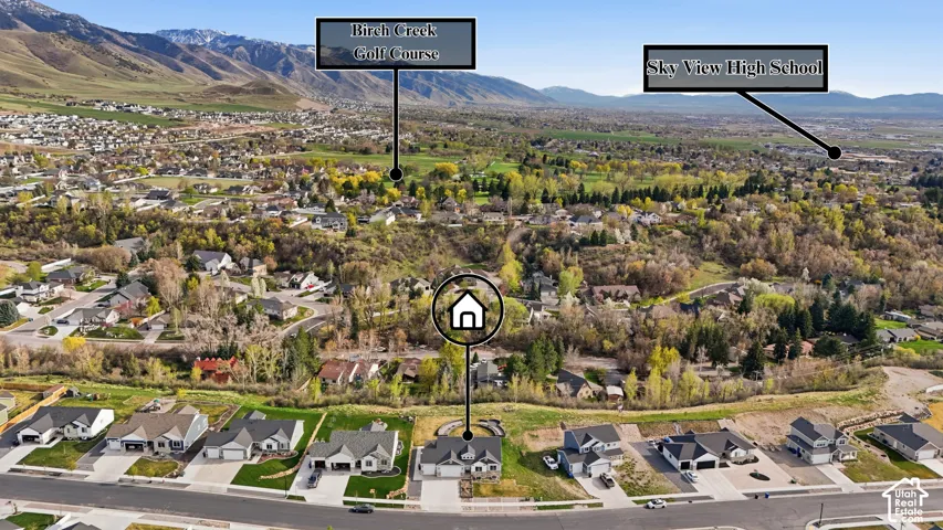 Aerial view showcasing this residence nestled within a tree-lined neighborhood setting, with mature landscaping surrounding the property