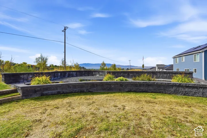 Multi-tiered hardscaped retaining walls featuring stacked stone-finish blocks, integrated landscaping beds, and a mountain backdrop