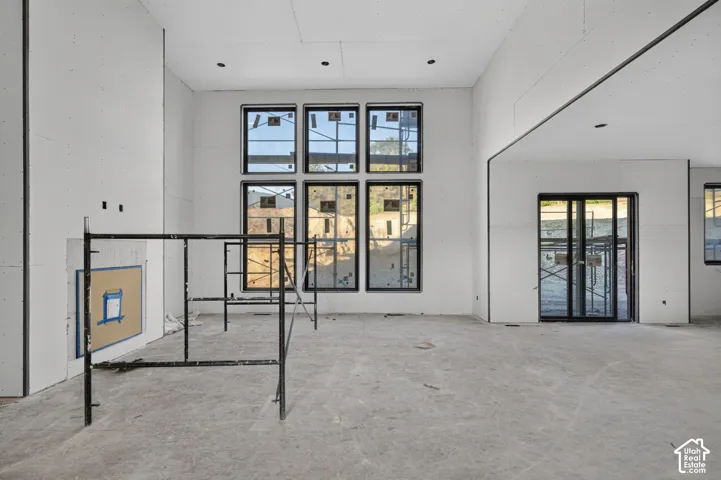 High-ceiling interior featuring a grid of six large windows with black frames, recessed lighting, and a glass-paneled door
