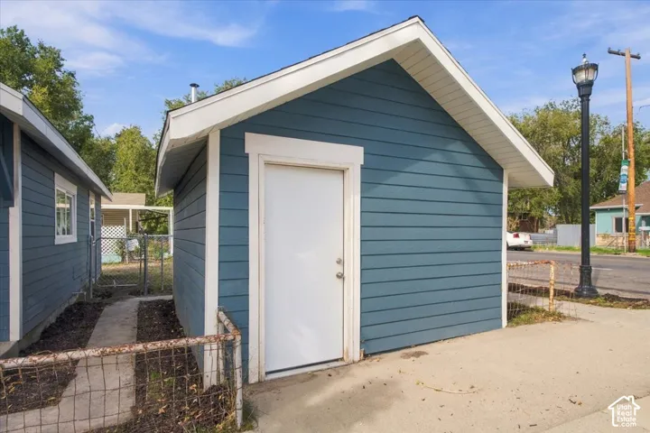 Detached structure with blue lap siding, gable roof, white trim, and a pedestrian door