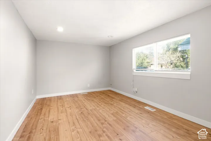 Interior room featuring wood-finish flooring, neutral wall paint, recessed lighting, and a large window