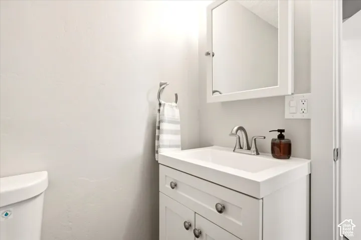 White vanity featuring a rectangular integrated sink, brushed metal dual-handle faucet, and built-in cabinet storage topped with a wall-mounted medicine cabinet