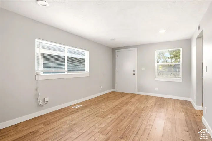 Wood-finish flooring, neutral wall paint, two windows with horizontal blinds, and recessed ceiling lighting