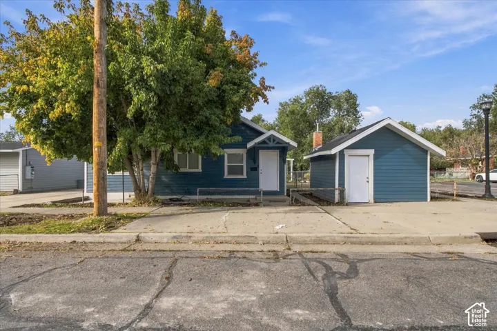 Blue-sided exterior featuring a gable roof, covered entryway, concrete driveway, and detached garage