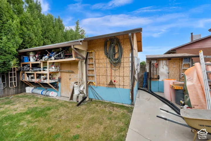 Exterior storage structures featuring wood-panel construction, built-in open shelving, and integrated rain gutters, complemented by a concrete walkway