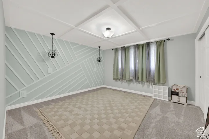 Room featuring a geometric wood-paneled accent wall, coffered ceiling, and dual pendant light fixtures