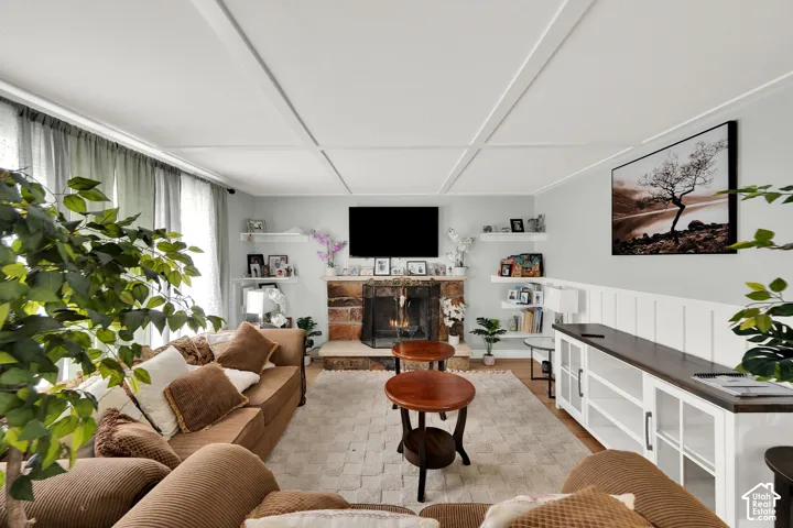 Living area featuring a coffered ceiling, stone-surround fireplace, built-in shelving, and board-and-batten wainscoting
