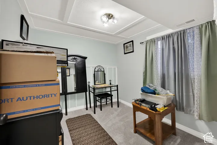 Room featuring a coffered ceiling, wall paneling, and neutral carpeting